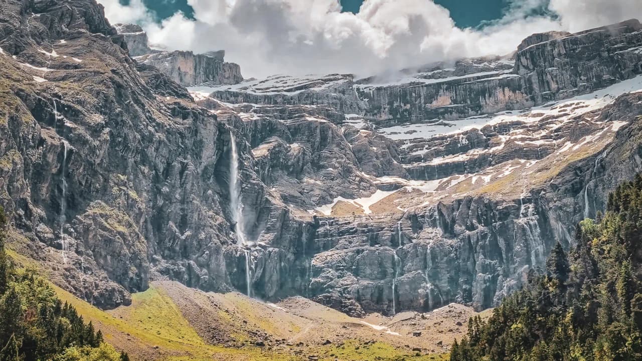 Prachtig landschap in het Gavarnie keteldal, met watervallen en majestueuze bergen onder een bewolkte hemel.