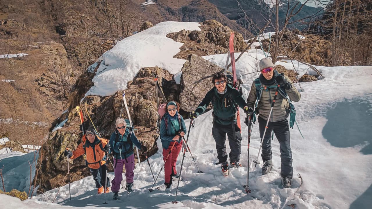 Groupe d'aventuriers en ski de randonnée sur neige, face au Mont Viso, dans un décor alpin.