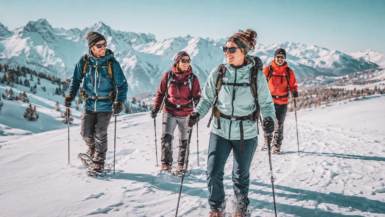 A group of friends out on snowshoes, laughing and exploring the magnificent snow-covered Hautes-Alpes.