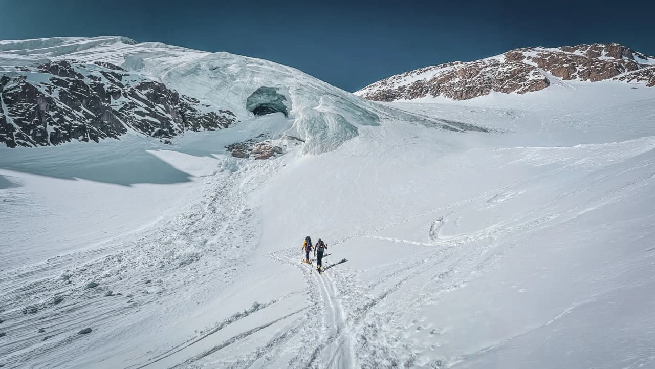 A group of skiers crossing a pristine glacier under a blue sky, a high mountain adventure.