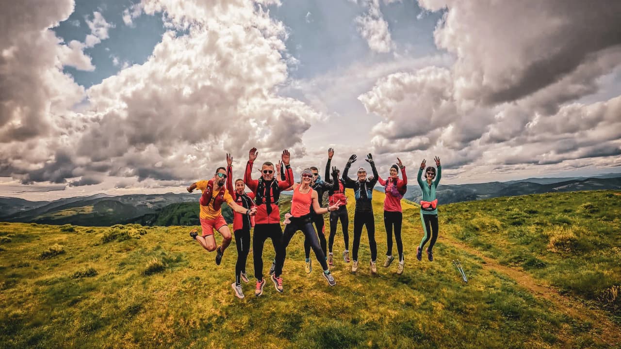 Groupe joyeux en randonnée dans les Vosges, sous un ciel nuageux, entouré de verdure.