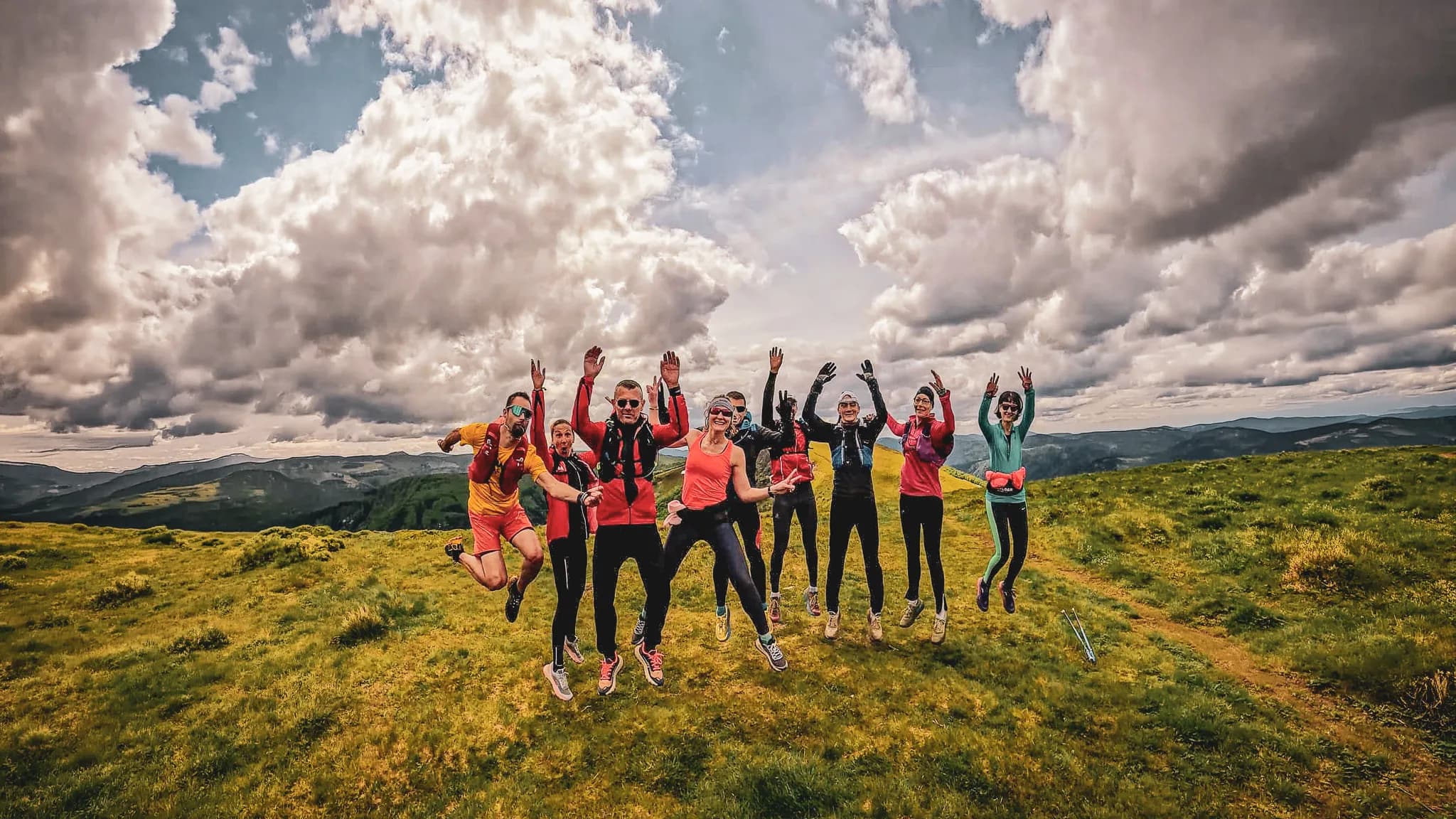 Groupe joyeux en randonnée dans les Vosges, sous un ciel nuageux, entouré de verdure.