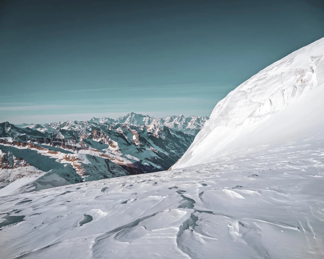 Panorama majestueux des Alpes, neige immaculée et sommets éblouissants sous un ciel bleu.