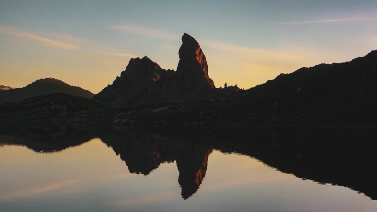 Reflet spectaculaire d'un sommet montagneux au crépuscule sur un lac calme, invitation à l'aventure.