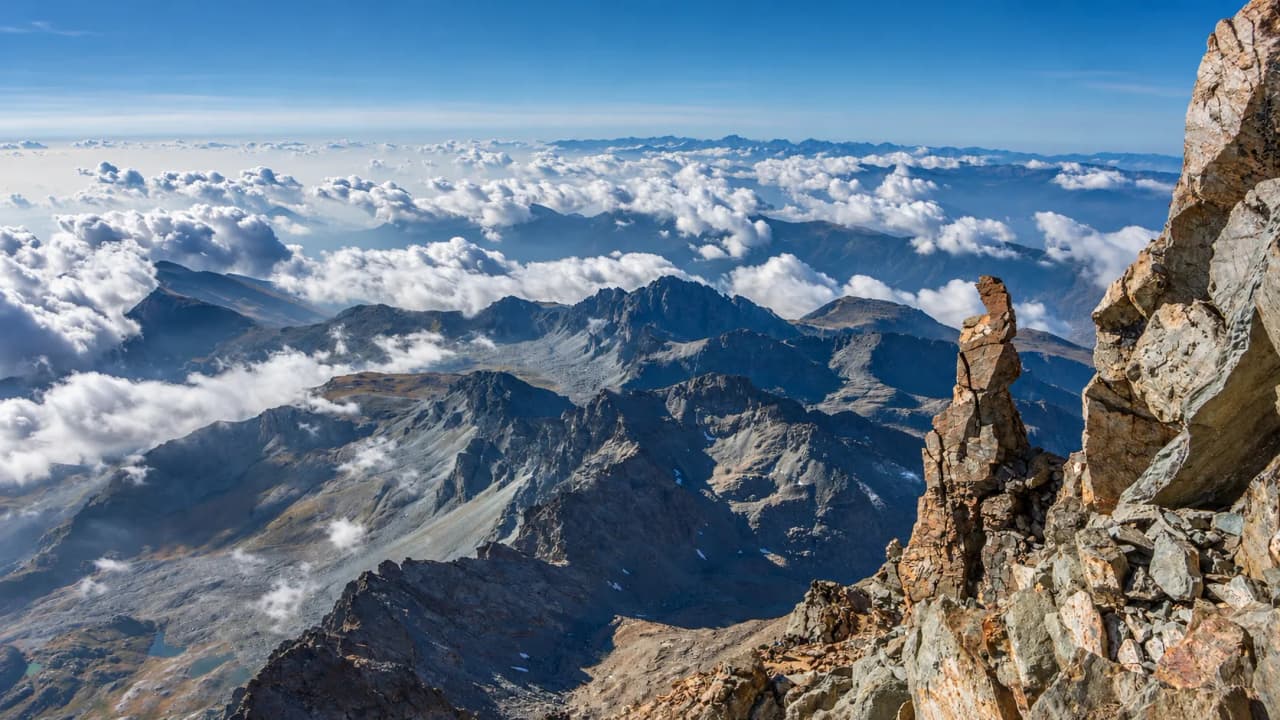 A panoramic view of Mount Viso, with its majestic peaks and a sky dotted with clouds.