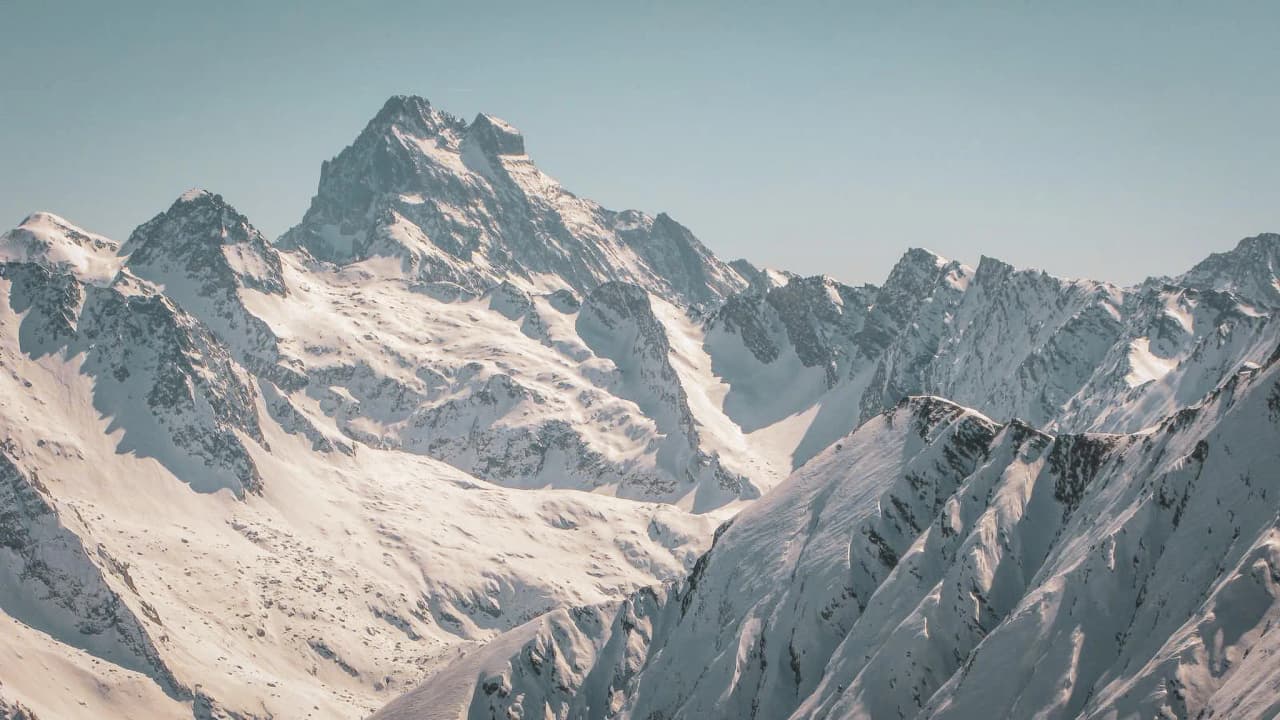 Majestic snow-capped mountains under clear skies, an invitation to alpine adventure.