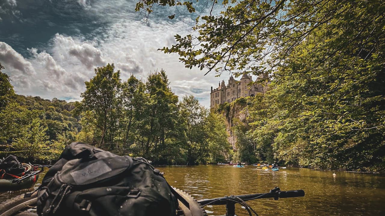 Peaceful view of the Lesse valley, between lush green forest and majestic castle above the river.