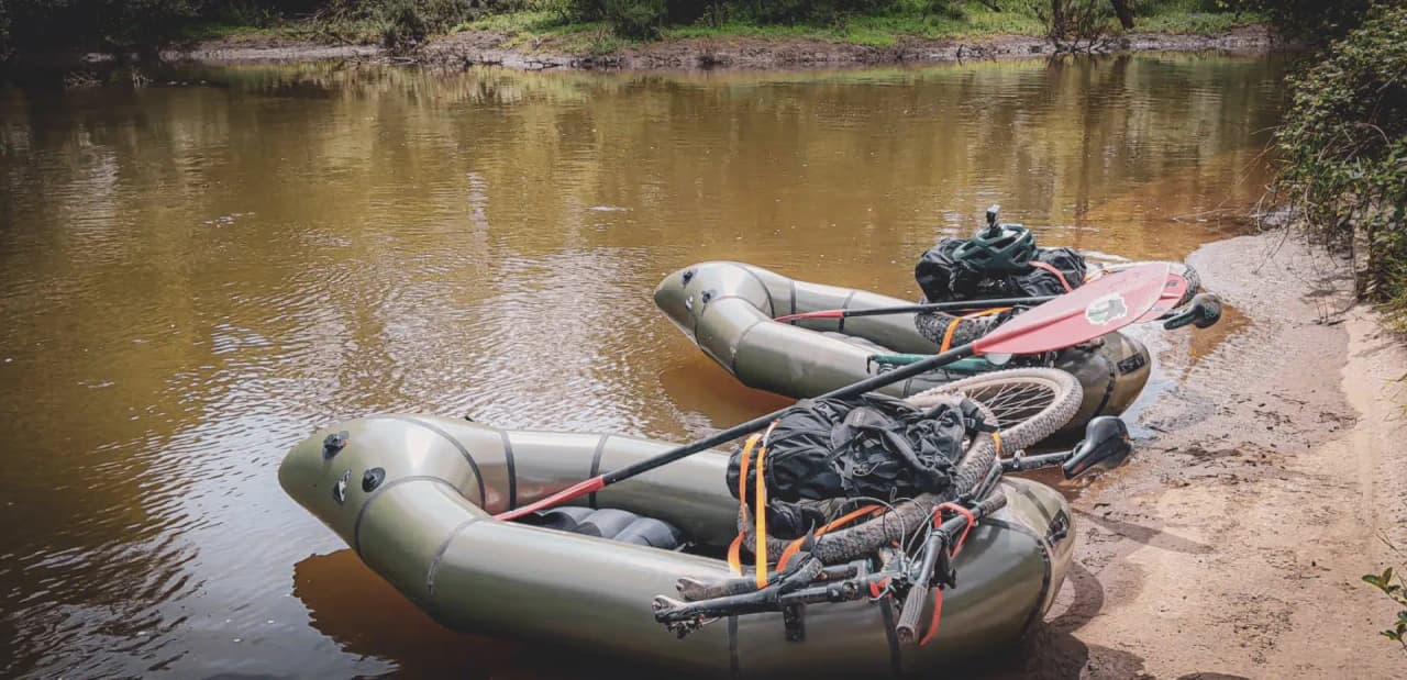 Two packrafts on the banks of a river, ready for an adventure in the heart of nature, surrounded by greenery.