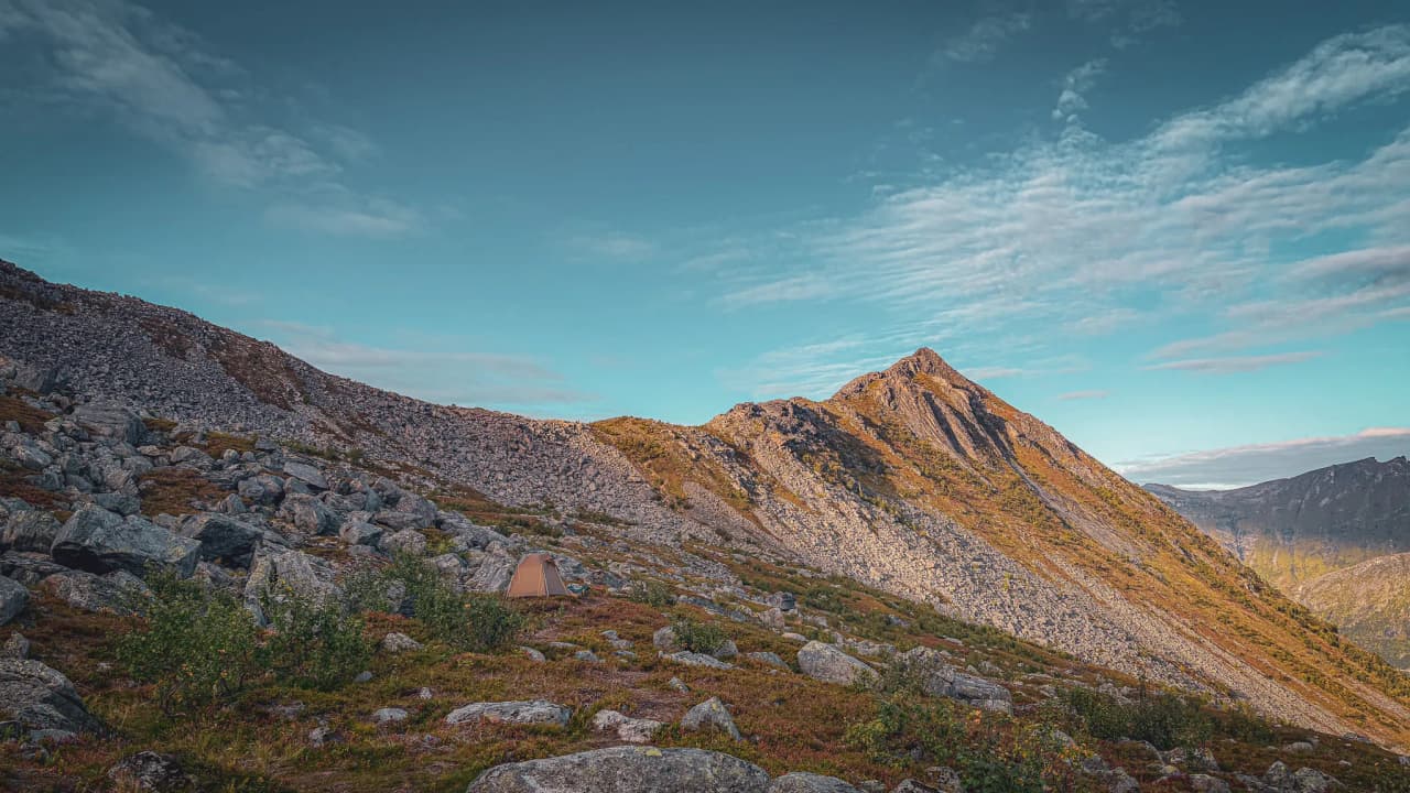 Het majestueuze landschap van het eiland Senja, met bergen, rotsen en een stralend blauwe lucht.