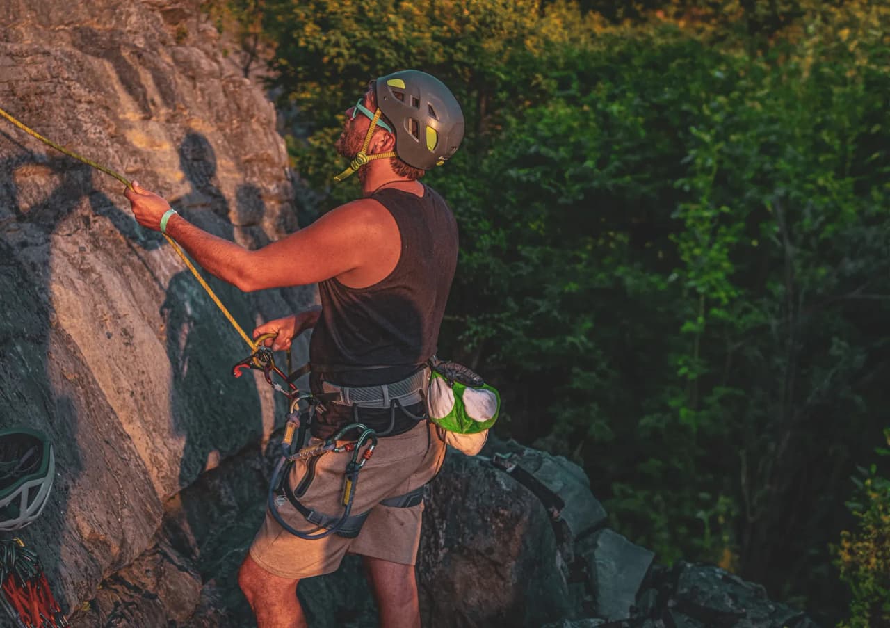 Climber in action on a rock face, under a golden mountain sunset sky.
