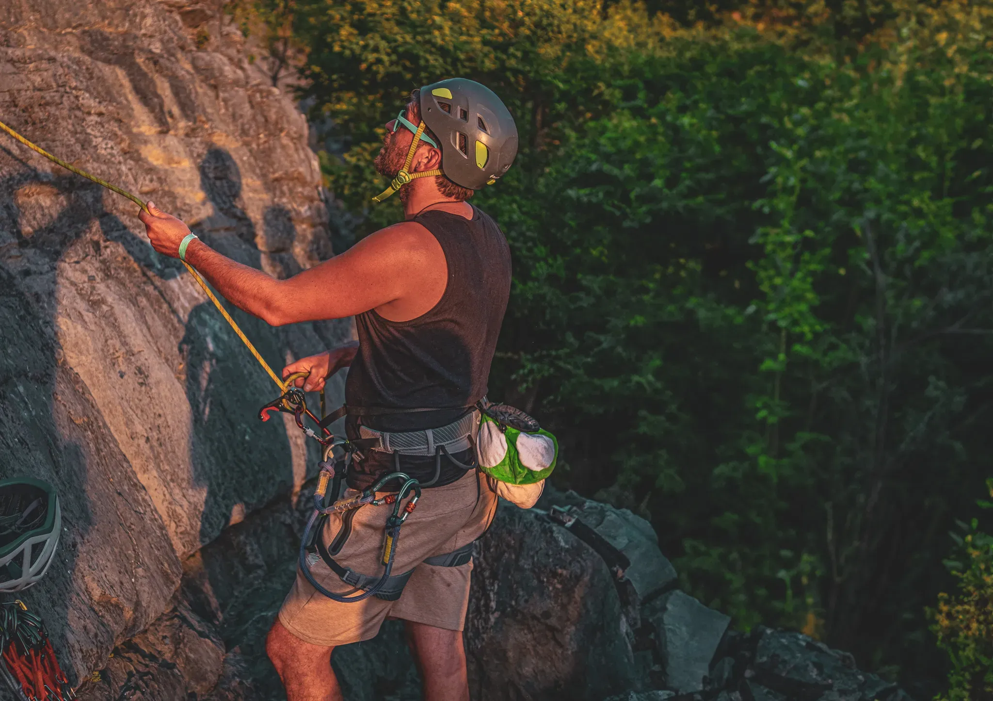 Climber in action on a rock face, under a golden mountain sunset sky.