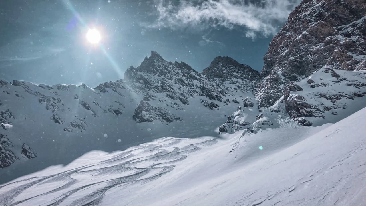 Un paysage alpin majestueux avec des montagnes enneigées et un soleil éclatant, invitation à l'aventure.