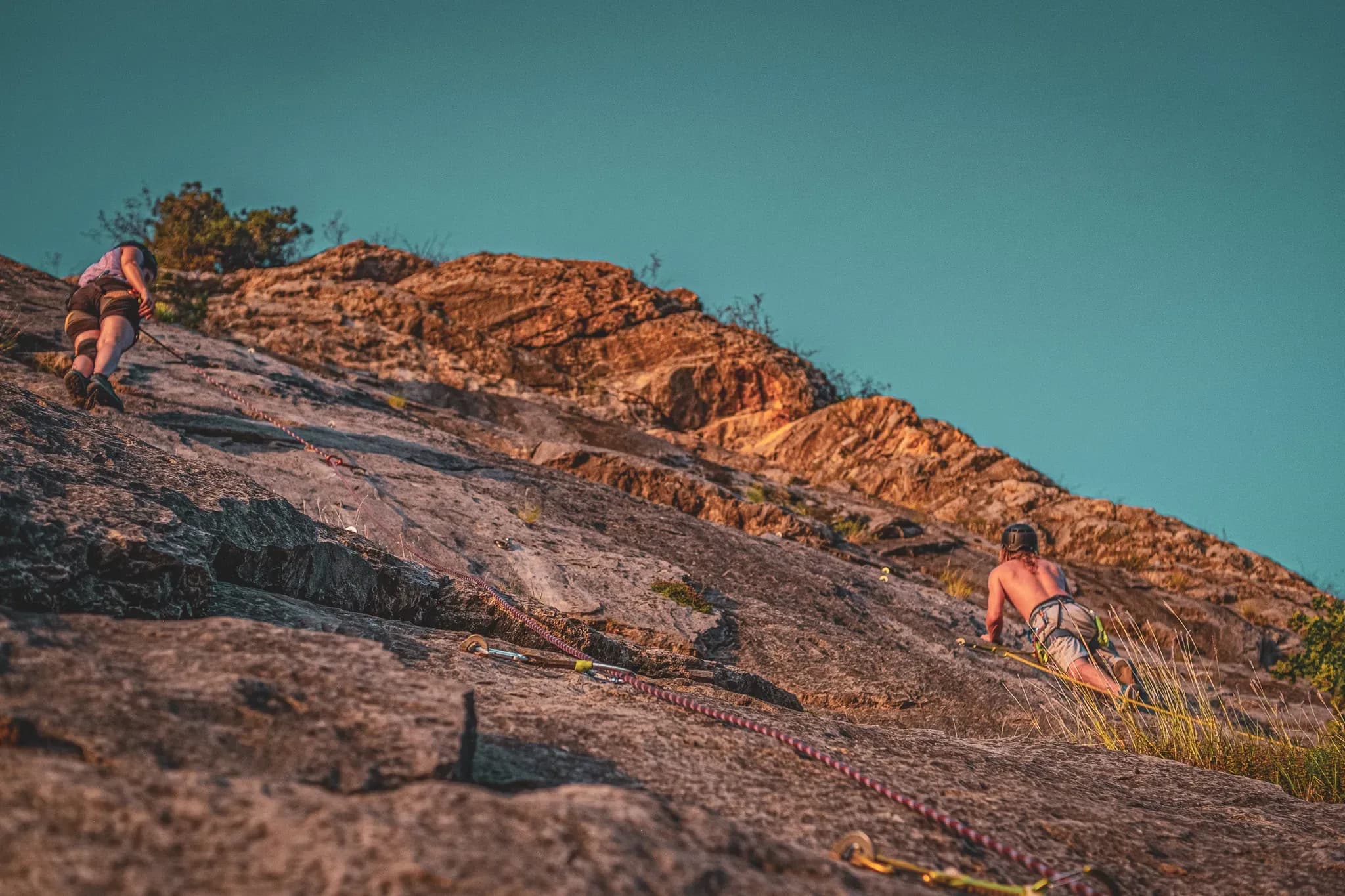 Climbers tackle a sun-drenched cliff, immersed in a spectacular Alpine landscape.