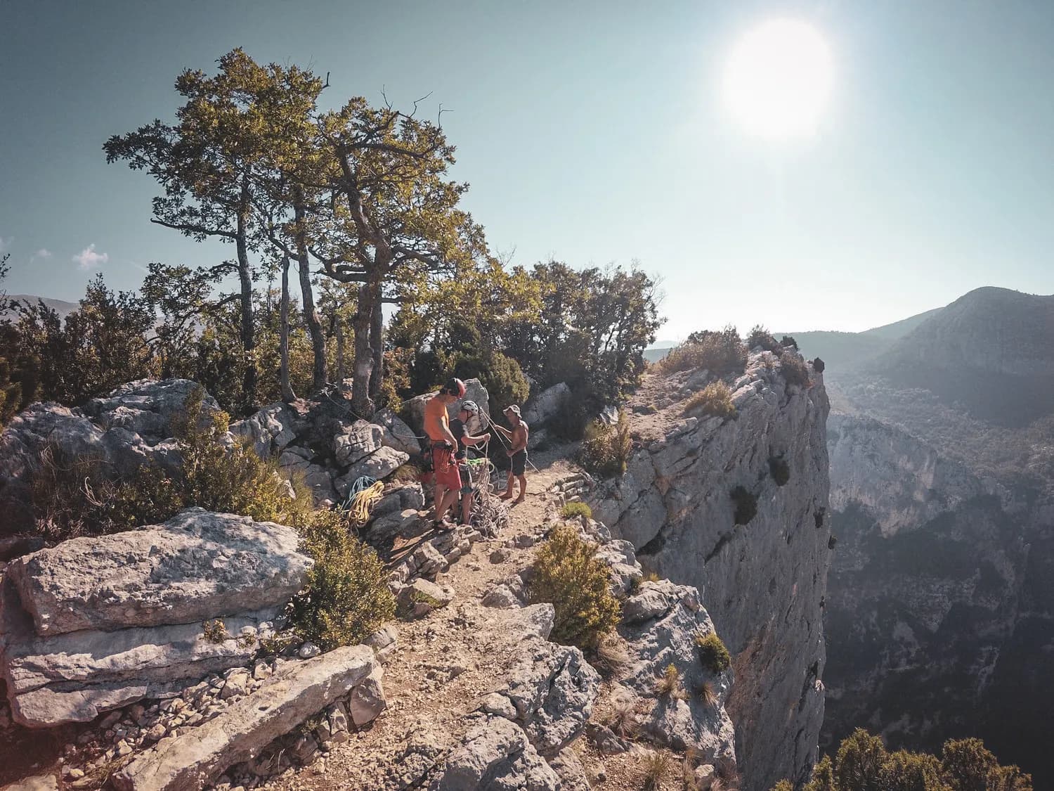 A climbing group on a rocky summit, surrounded by magnificent scenery and radiant light.