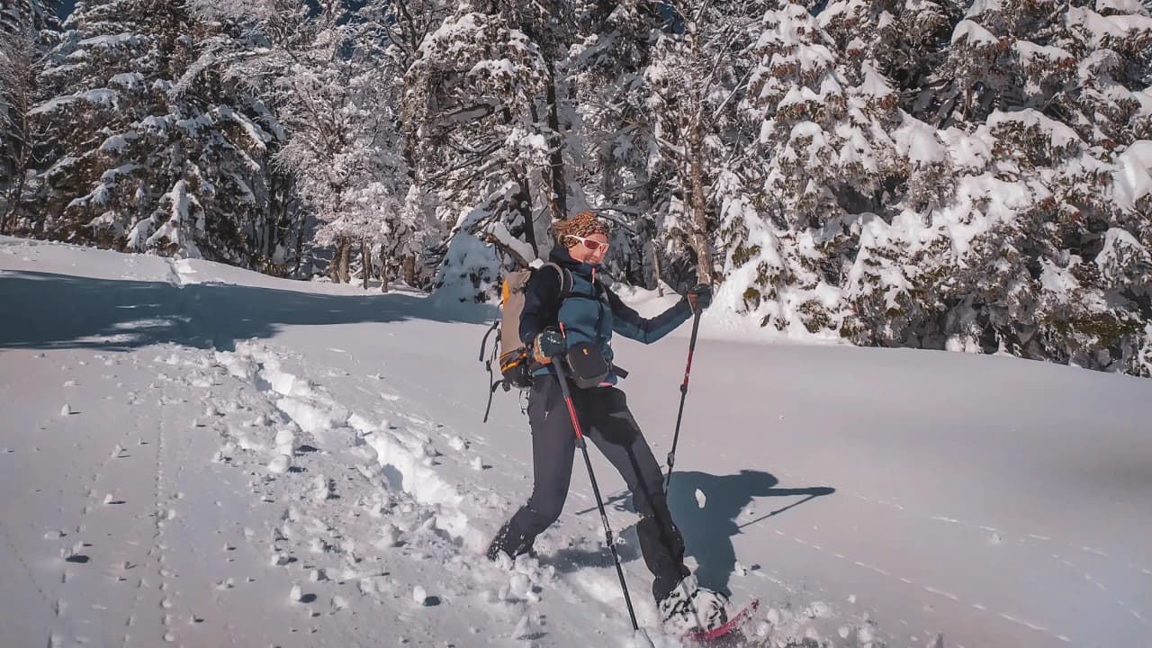 Femme en raquettes marchant dans la neige vierge, entourée de paysages enneigés du Vercors.