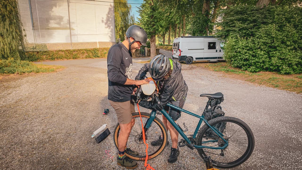 Two adventurers prepare their mountain bikes for a memorable expedition between forest and river.