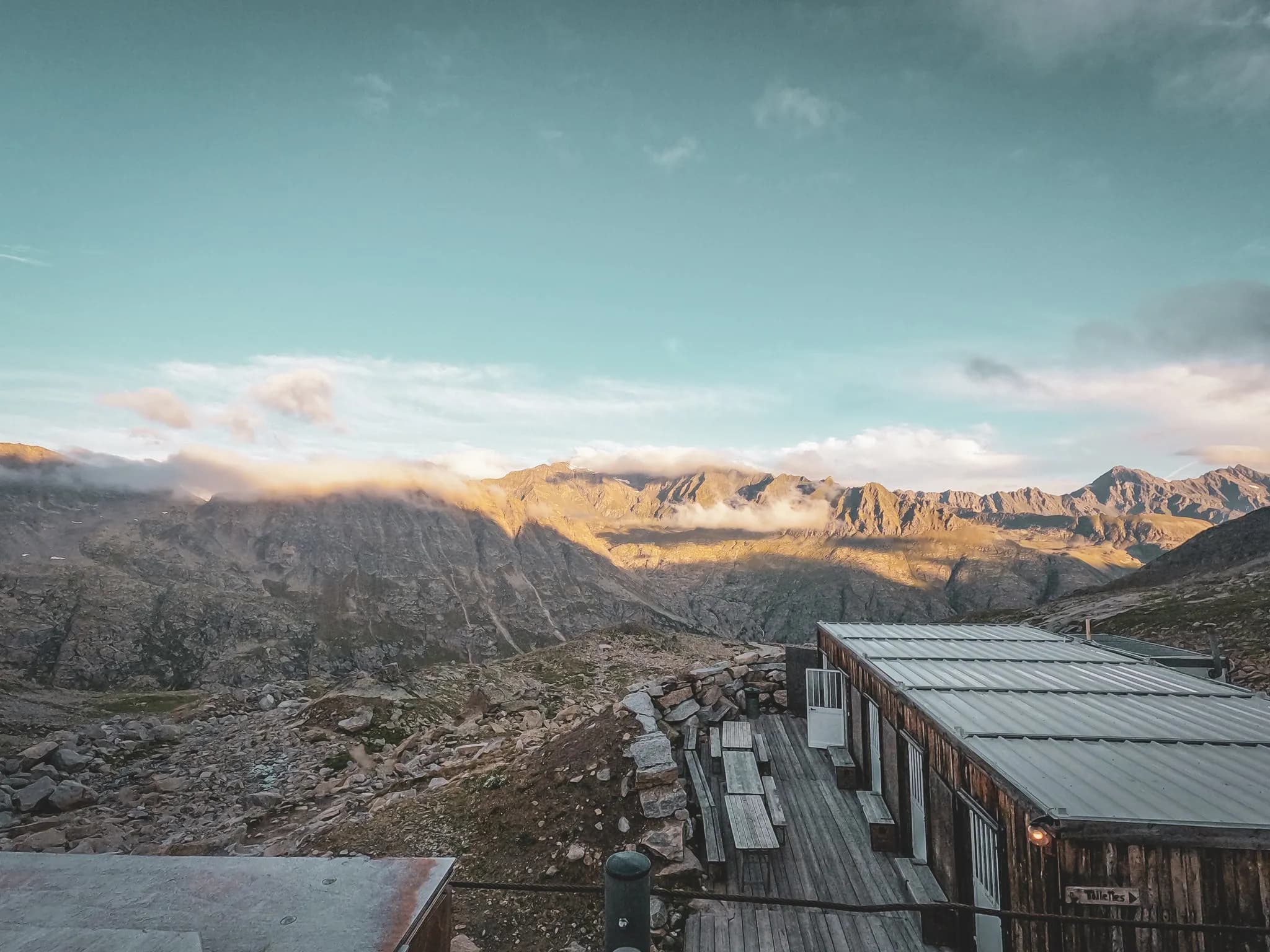 Panoramic view of the mountains under a clear sky, warm shelter in the foreground. An Alpine escape!