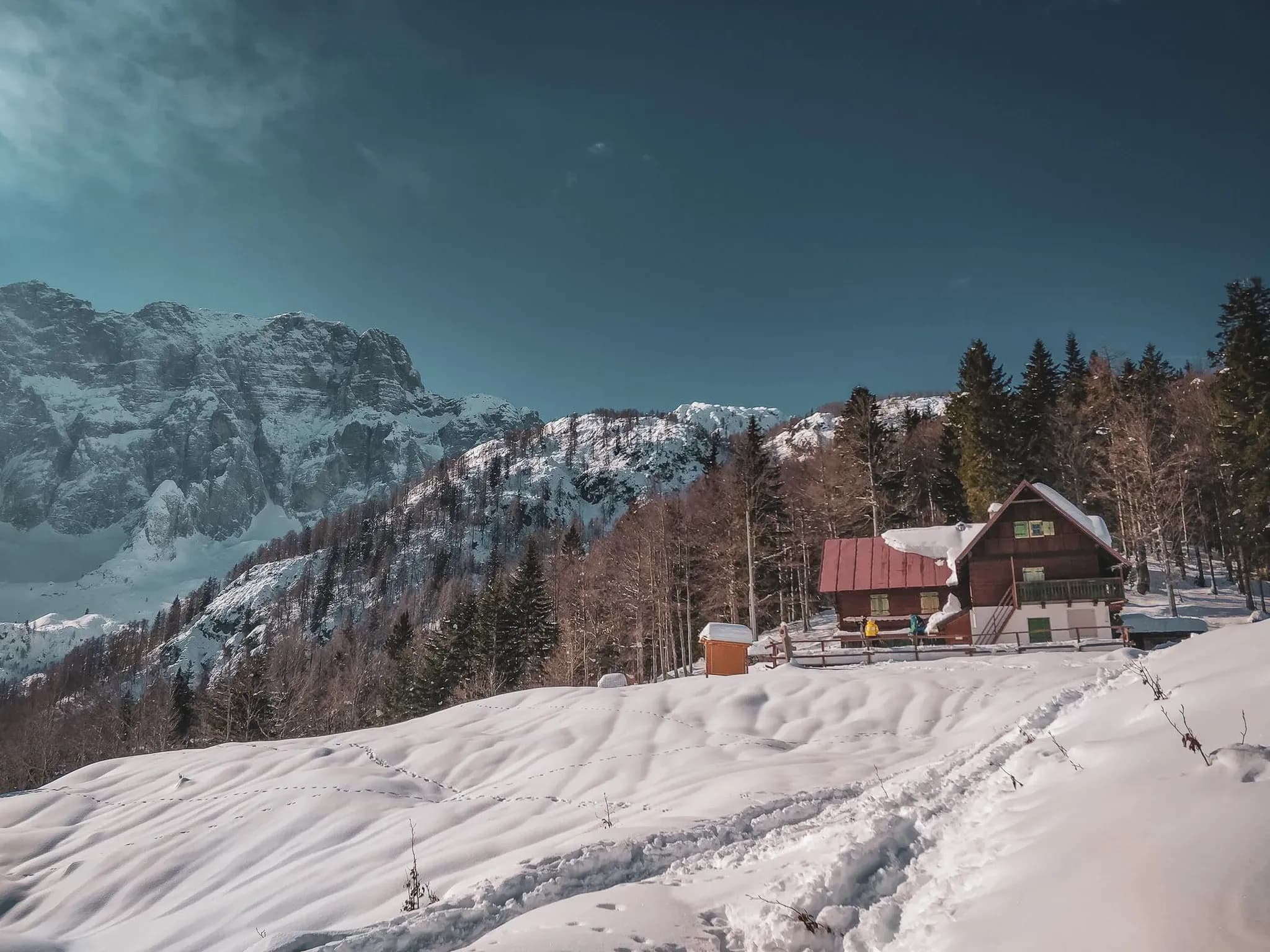 Merveilleux chalet entouré de neige dans les Alpes juliennes, avec des montagnes majestueuses en arrière-plan.