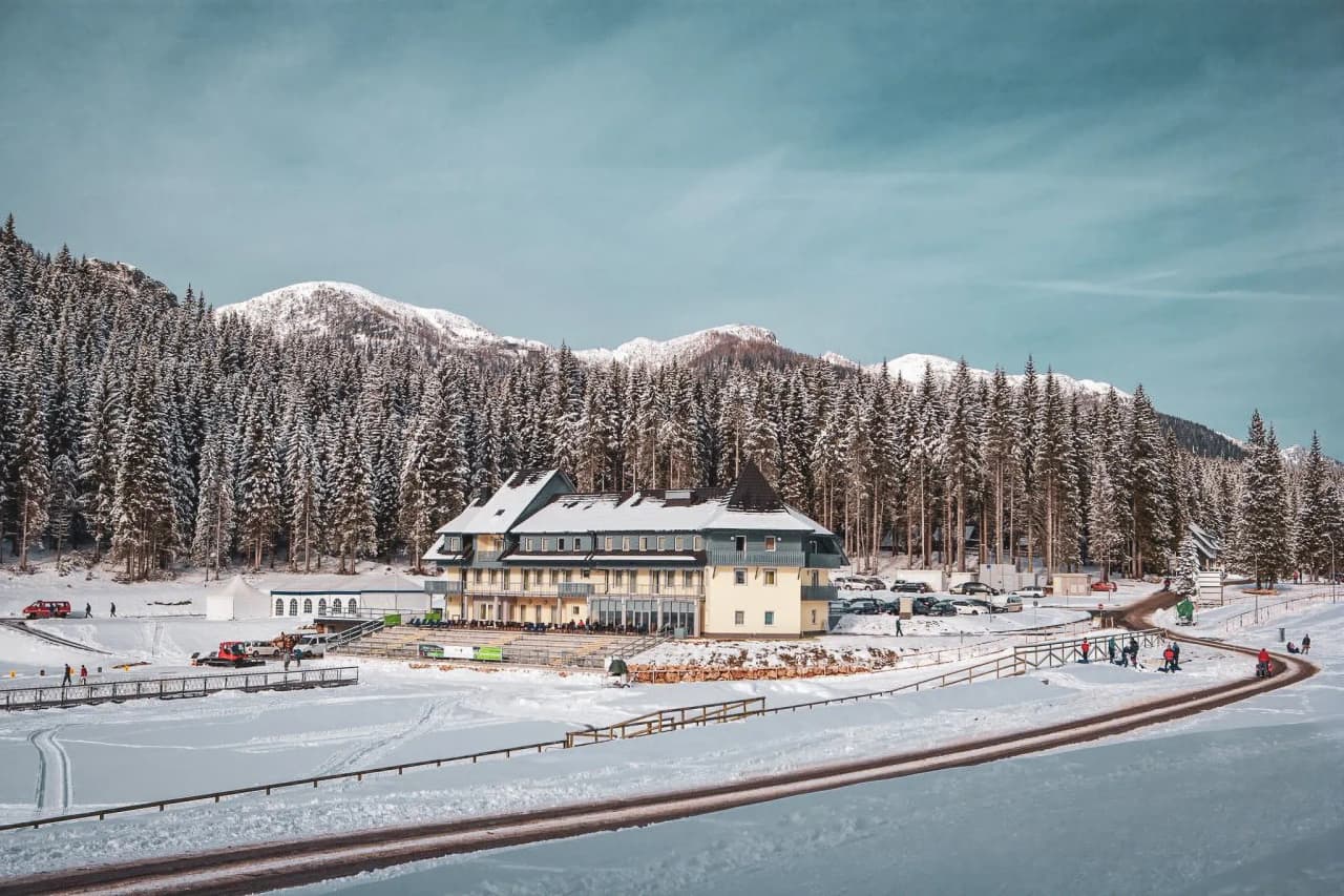Hôtel pittoresque dans les Alpes juliennes, entouré de forêts enneigées et de montagnes majestueuses.