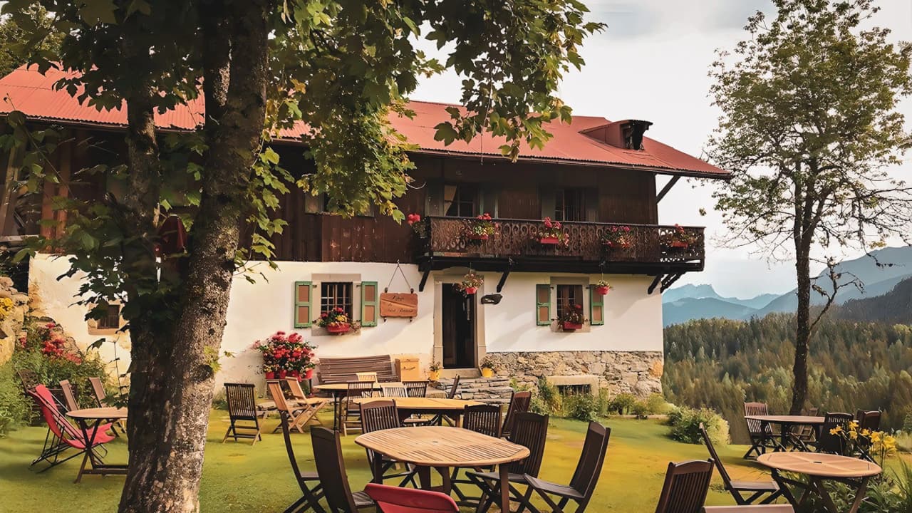 Cosy mountain hut surrounded by flowers, with terrace and panoramic mountain views.