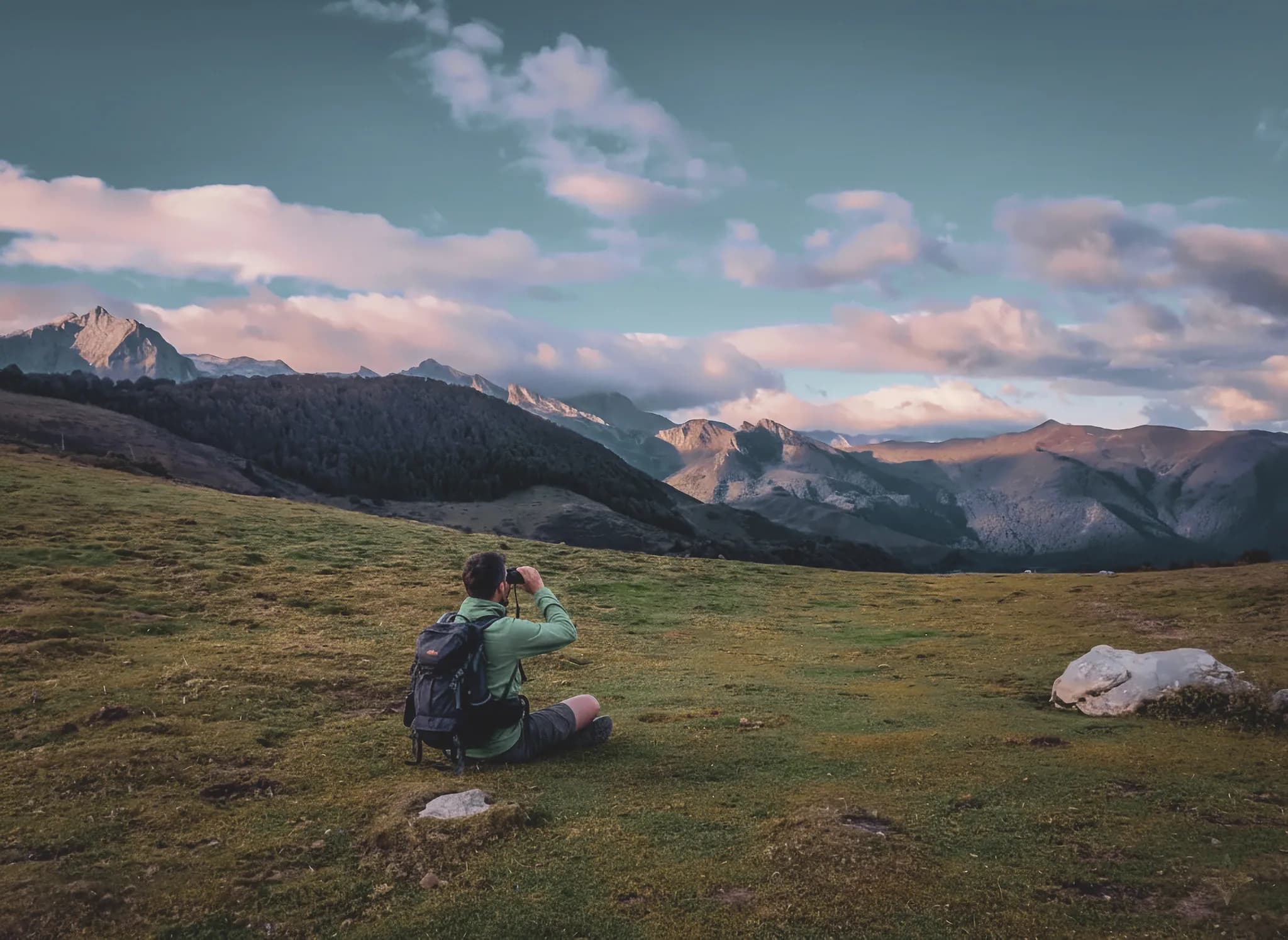 Wandelaar overdenkt de majestueuze bergen van de Pyreneeën bij zonsondergang.