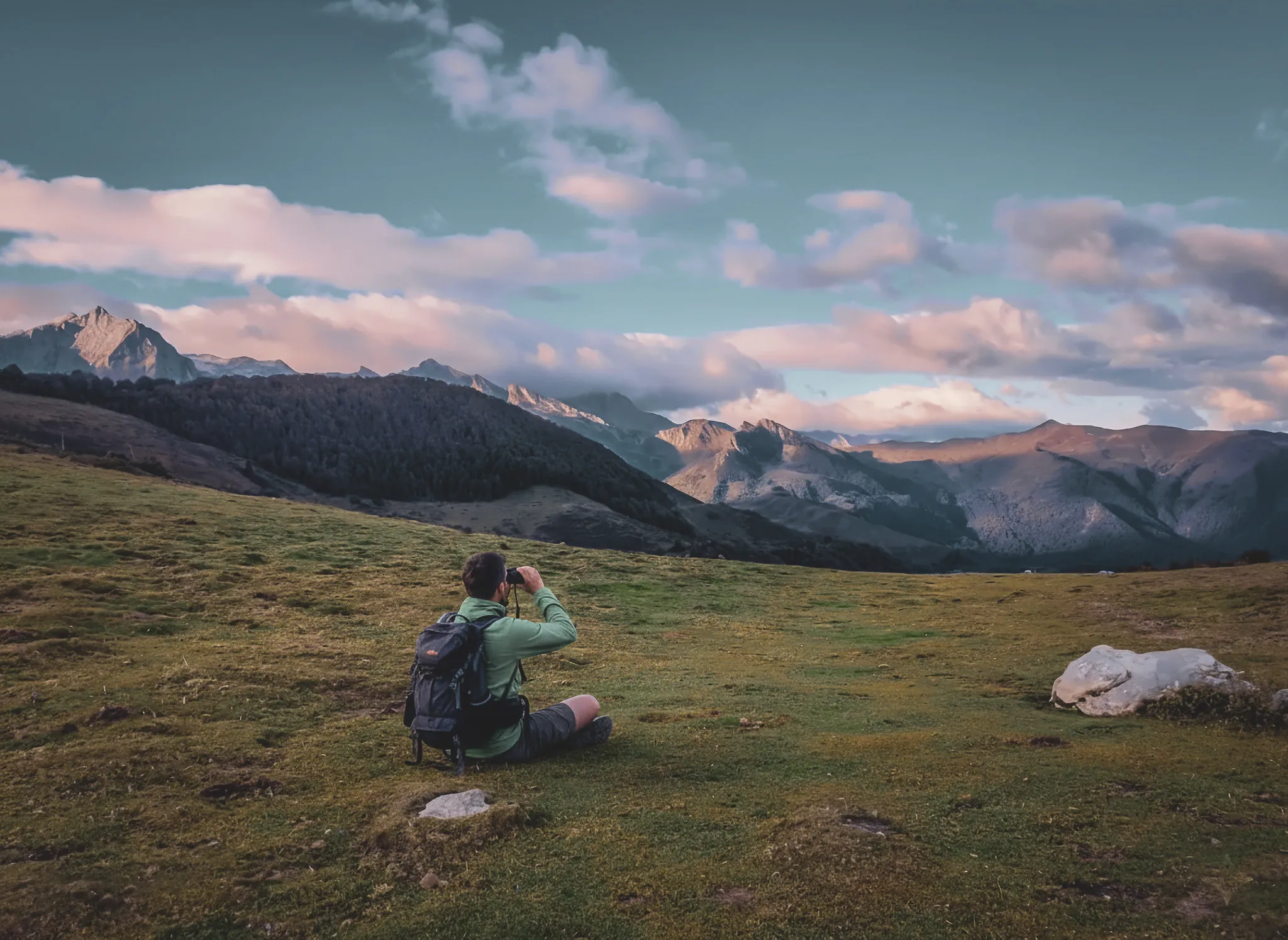 Wandelaar overdenkt de majestueuze bergen van de Pyreneeën bij zonsondergang.