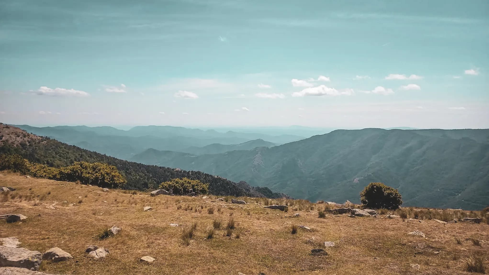 Landschappen van de Cevennen, groene heuvels, blauwe lucht en verspreide wolken, een uitnodiging om te reizen.