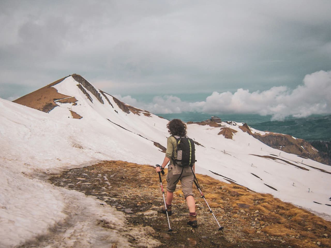 A hiker on a mountain trail, surrounded by eternal snow and volcanic landscapes.