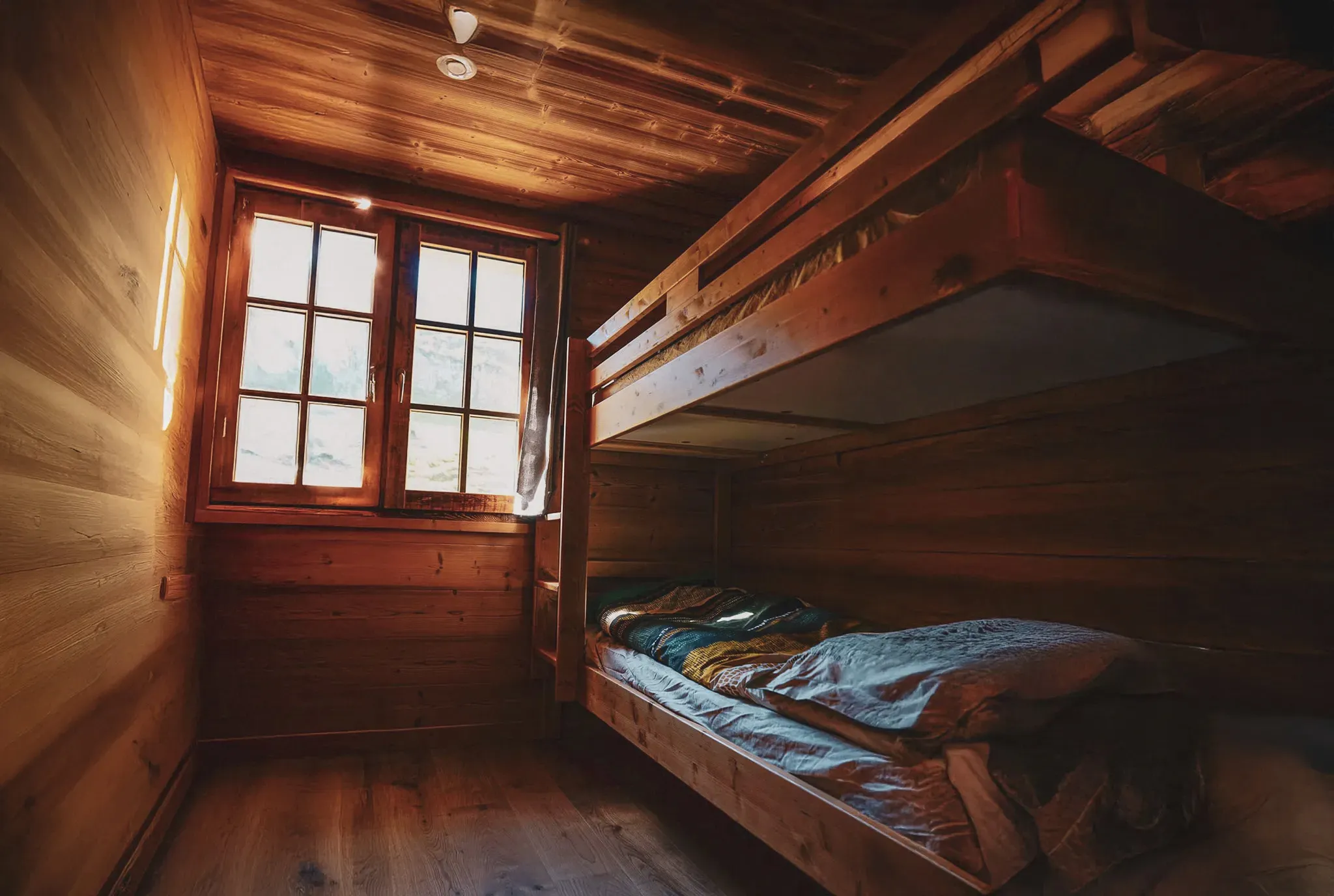 A cosy wooden room with bunk beds and natural light, ideal for an alpine break.