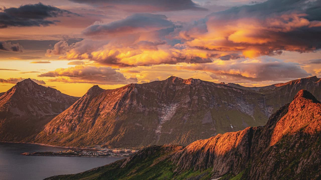 Zonsondergang over majestueuze bergen, omgeven door een rustige fjord.