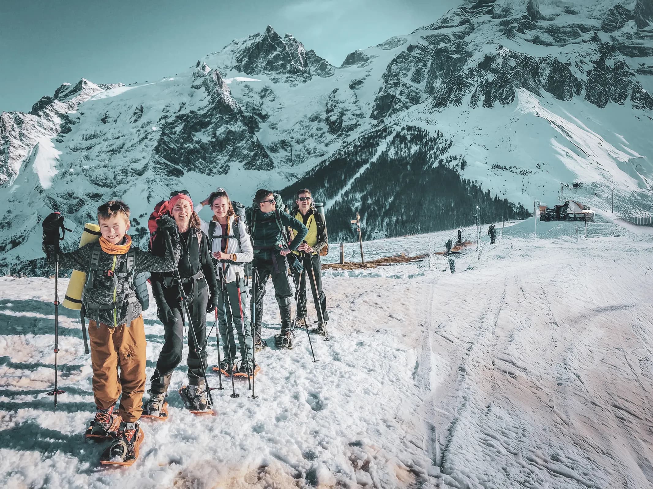 Un groupe joyeux en raquettes dans un paysage alpin enneigé, prêt pour l'aventure.