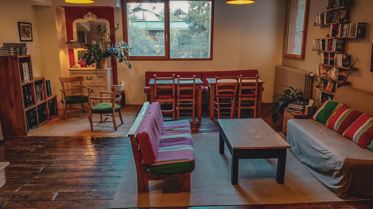 Espace accueillant avec canapé coloré, chaises et lumière naturelle, parfait pour se détendre après l'aventure.