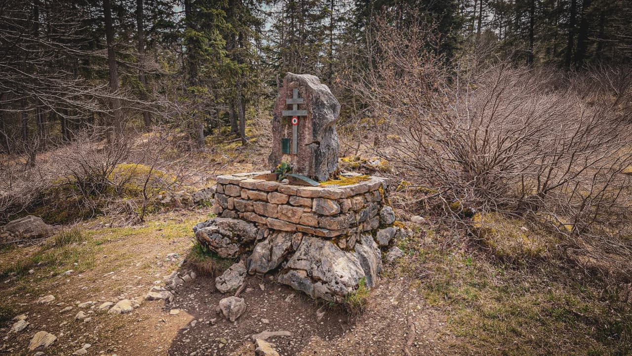 Un fontaine en pierre entourée d'arbres, évoquant la tranquillité des forêts du Vercors.
