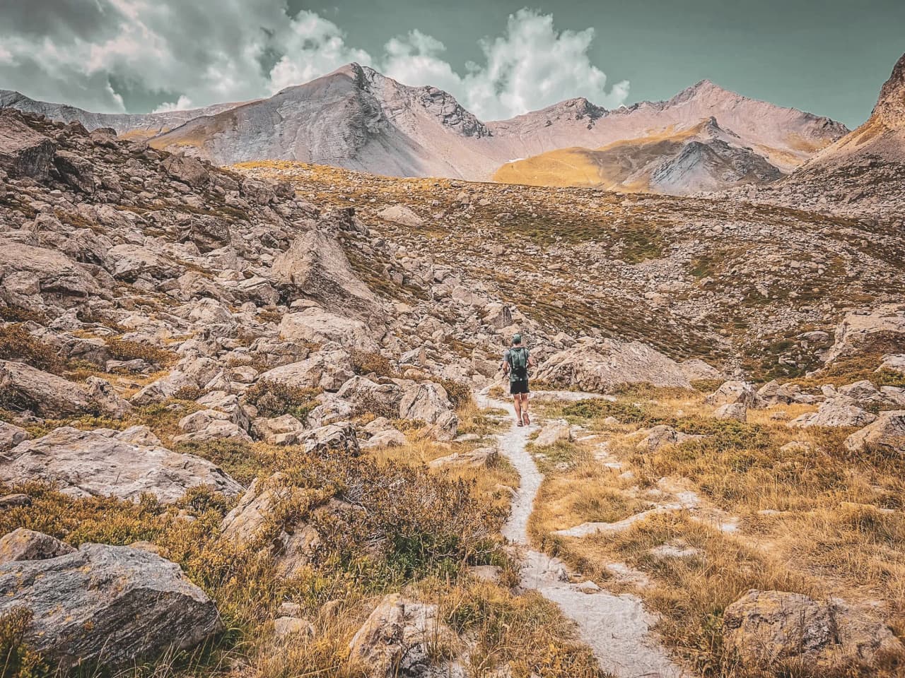 Randonneur sur un sentier parmi des paysages rocheux et majestueux des Écrins.