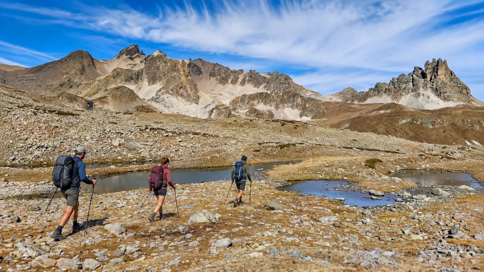 Three walkers are hiking through a picturesque alpine landscape on Mount Thabor, under a blue sky.