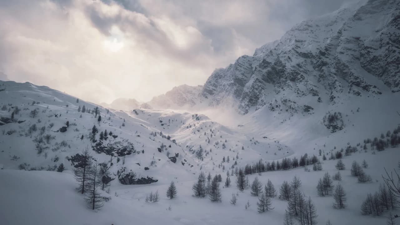 Snow-covered Alpine scenery under cloudy skies, perfect for adventurous ski touring.