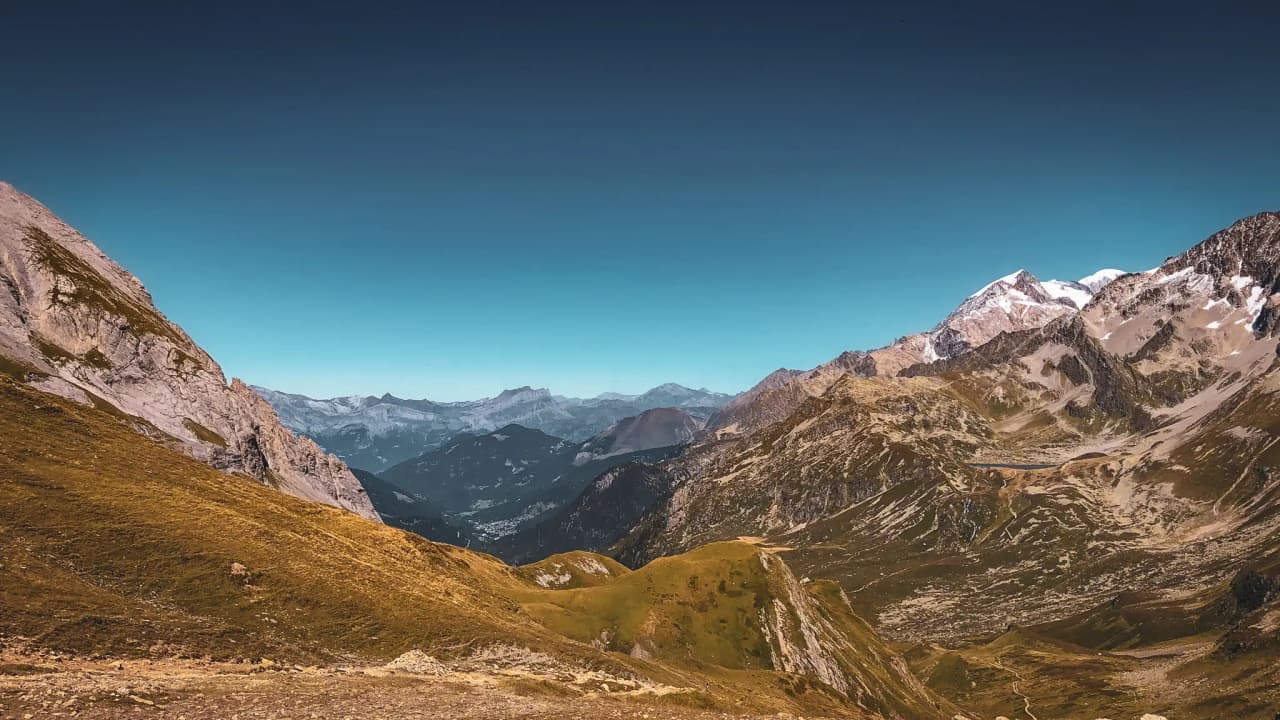 A majestic panorama of the mountains around Mont Blanc, with lush green valleys and brilliant blue skies.