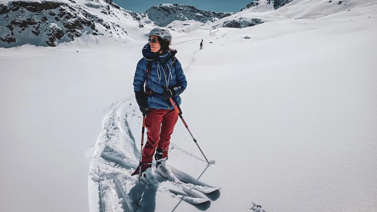 Skieuse en randonnée au Mont Viso, paysage enneigé majestueux sous un ciel bleu éclatant.