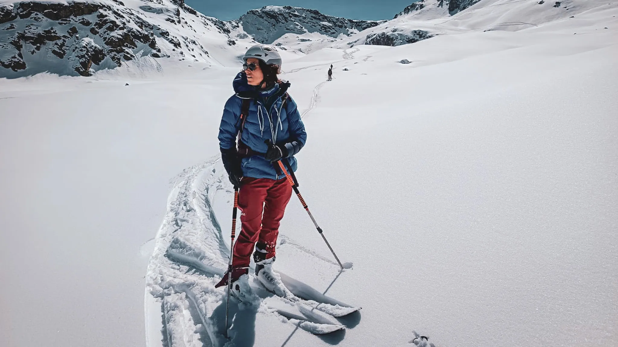 Skieuse en randonnée au Mont Viso, paysage enneigé majestueux sous un ciel bleu éclatant.