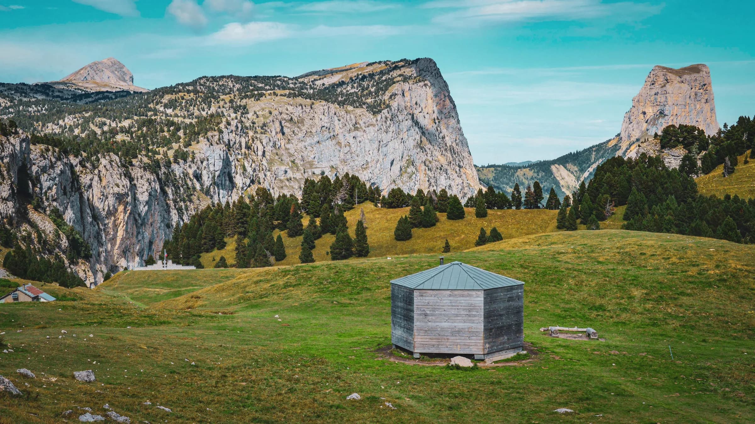 Un chalet en bois dans un paysage de montagnes verdoyantes, invitant à l'aventure en nature.
