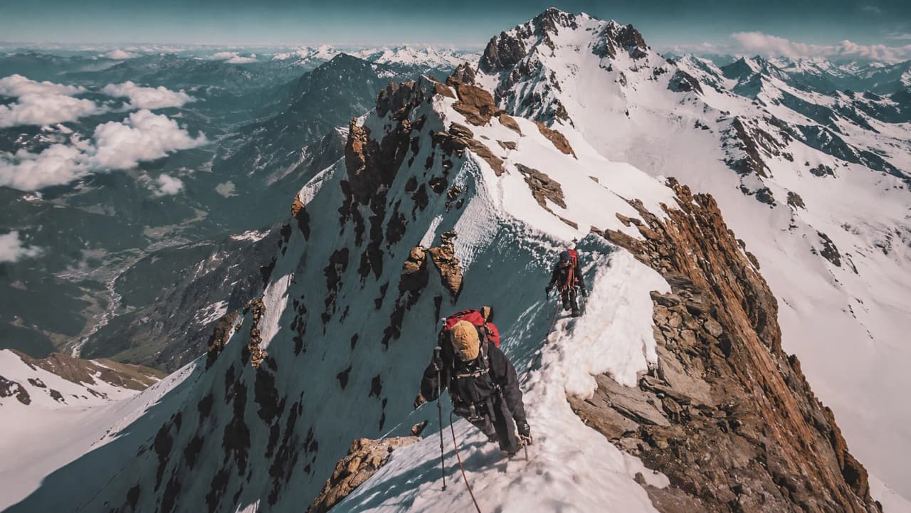 Bergbeklimmers steken een besneeuwde top over met uitzicht op een adembenemend panoramisch uitzicht op de gletsjers.