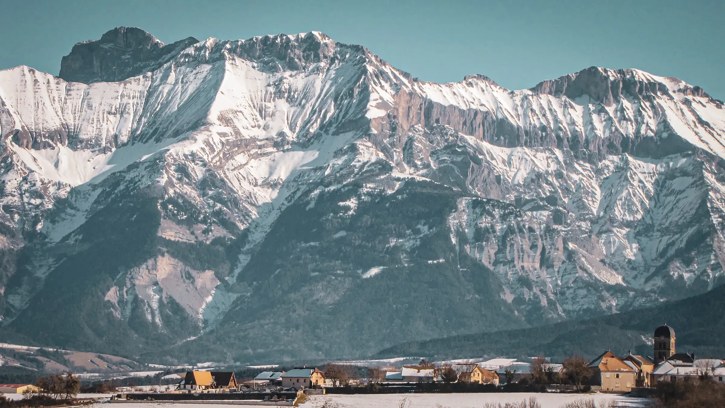 Majestic snow-capped mountains under clear skies, an idyllic landscape for adventurers.