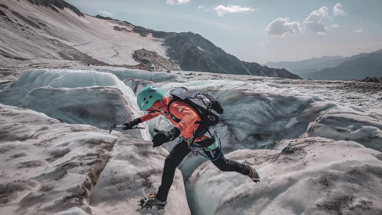 Alpiniste traversant un glacier éclatant sous le ciel bleu à Chamonix, prêt pour l'aventure.
