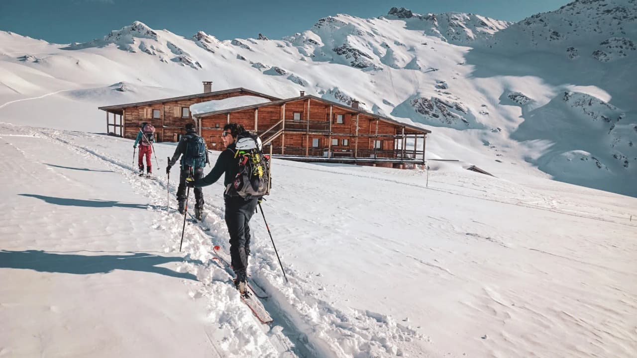 Groupe de randonneurs skiant sur la neige immaculée, avec les majestueuses montagnes en arrière-plan.