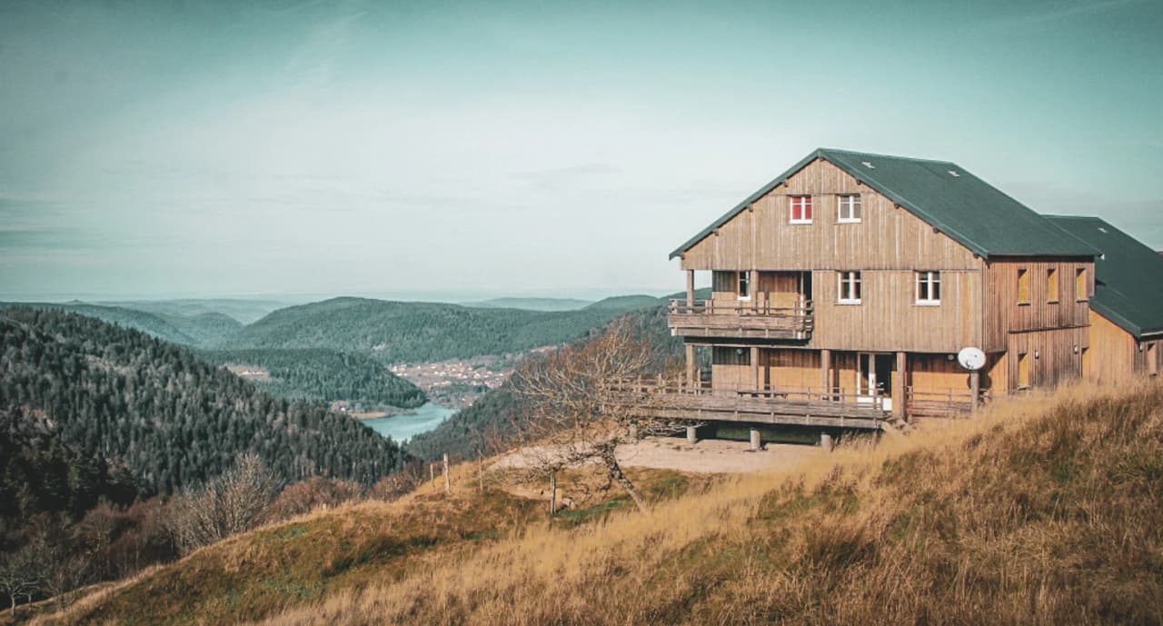 A wooden Mountain hut overlooking rolling countryside, perfect for a nature getaway.