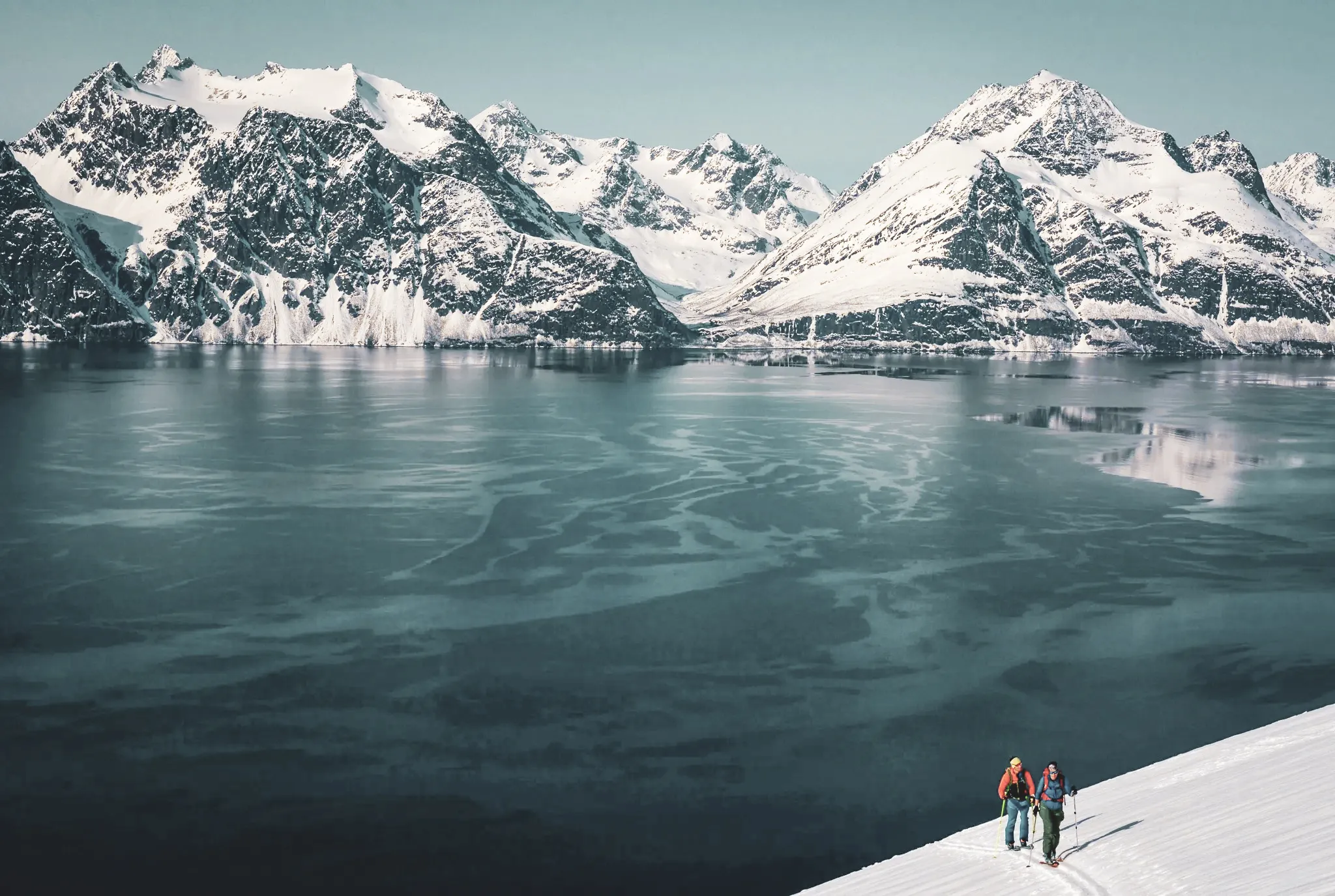 Ski touring in the Lyngen Alps, with snow-capped mountains and a sparkling fjord.