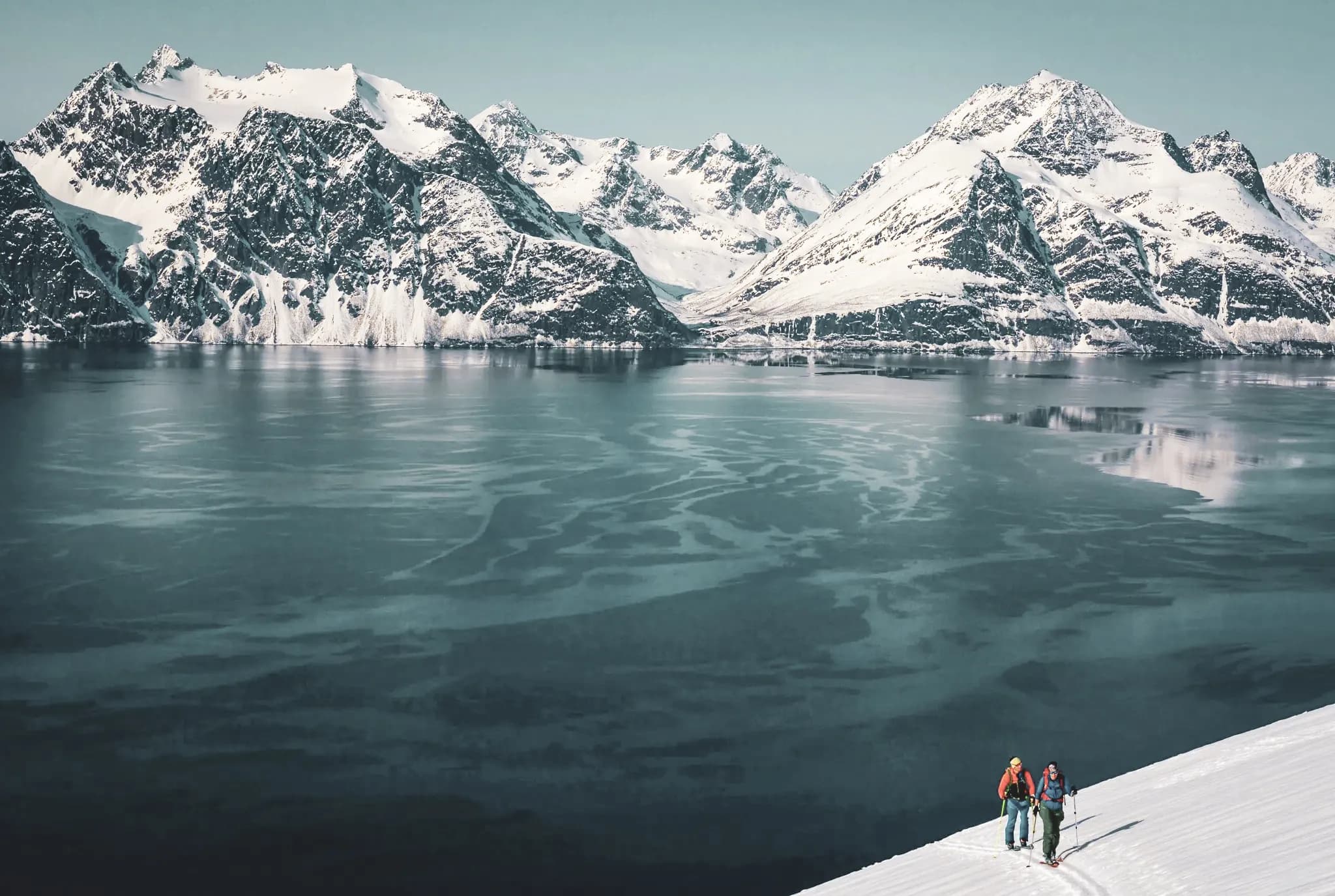Ski touring in the Lyngen Alps, with snow-capped mountains and a sparkling fjord.