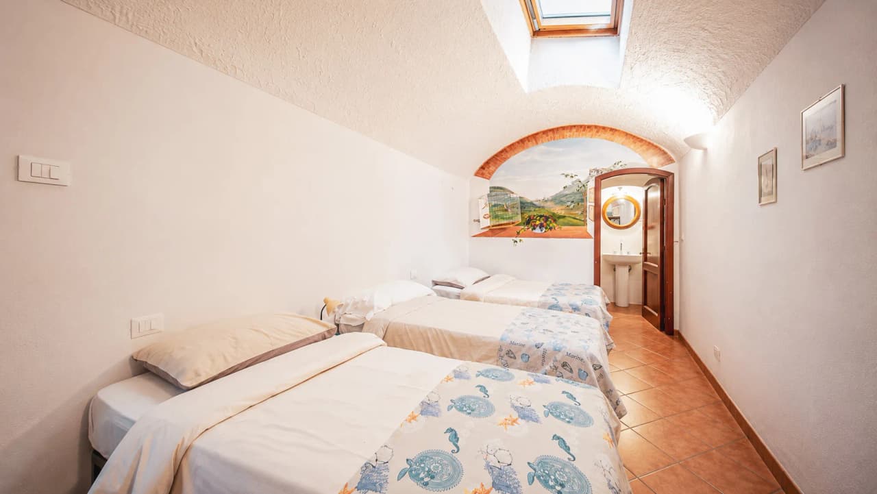 A cosy room with three beds, decorated with a view of the countryside, ideal for a Mediterranean holiday.
