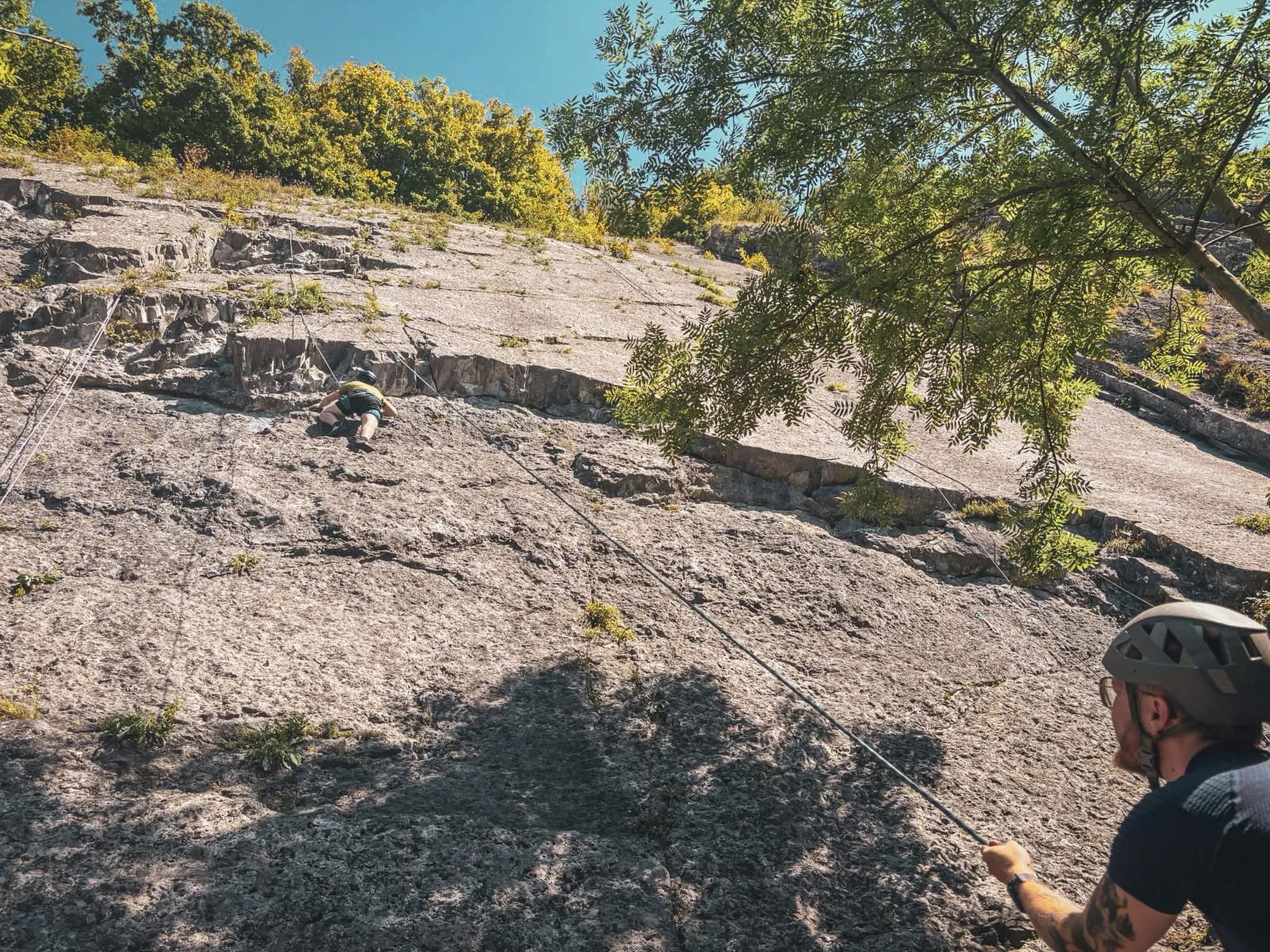 Captivating cliff-climbing at Yvoir, under blue skies and a lush natural backdrop.