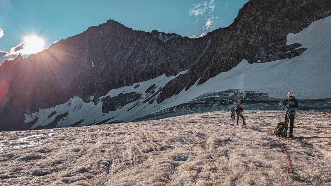 Alpinistes en pleine exploration sur un glacier ensoleillé des Écrins, majestueux sommets en arrière-plan.